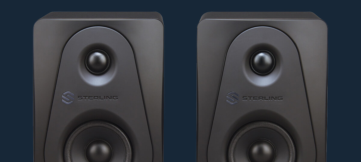 Sterling Audio MX3 3-inch powered studio monitor pair front top on blue background close up.